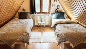 A cozy attic bedroom with two single beds, a small table, and a window with curtains. - Waldrauschen by Interhome (Bad Arolsen)