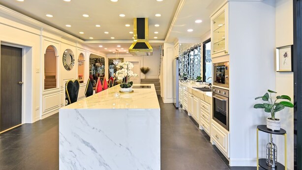 A modern kitchen with a marble island, stainless steel appliances, and a decorative plant. - Exquisite Pool Villa A  (Pattaya)