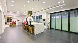 A modern kitchen with a marble island, recessed lighting, and a dining area with chairs and a table. - Exquisite Pool Villa A  (Pattaya)