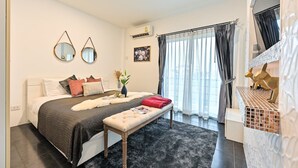 A modern bedroom with a large bed, bedside tables, a bench, and a view of the outdoors. - Exquisite Pool Villa A  (Pattaya)