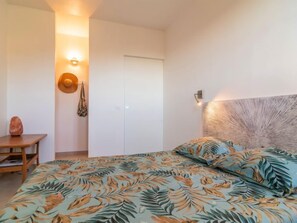 Een slaapkamer met een bed, nachtkastje, wandlamp en een deur.