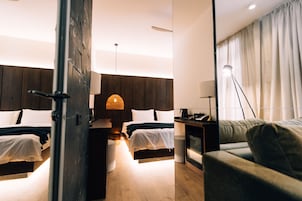 Una habitación de hotel moderna con dos camas, un sofá, un escritorio y una lámpara.