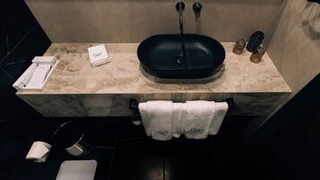 A bathroom with a black sink, marble countertop, and a towel rack with folded towels.