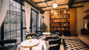 A modern living room with a large bookshelf, leather sofas, and a Christmas tree. - FORest 1961 Hotel & Restaurant (Vanadzor)