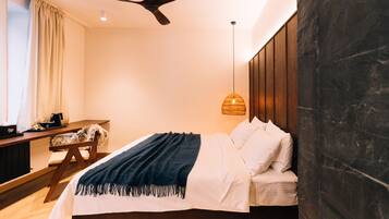 A modern bedroom with a bed, a desk, and a ceiling fan.