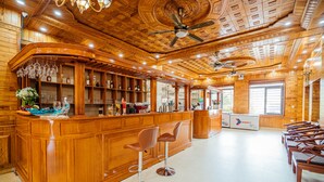 A bar area with wooden paneling, bar stools, and a ceiling fan. - Nam Hong Hotel (Binh Nguyen)