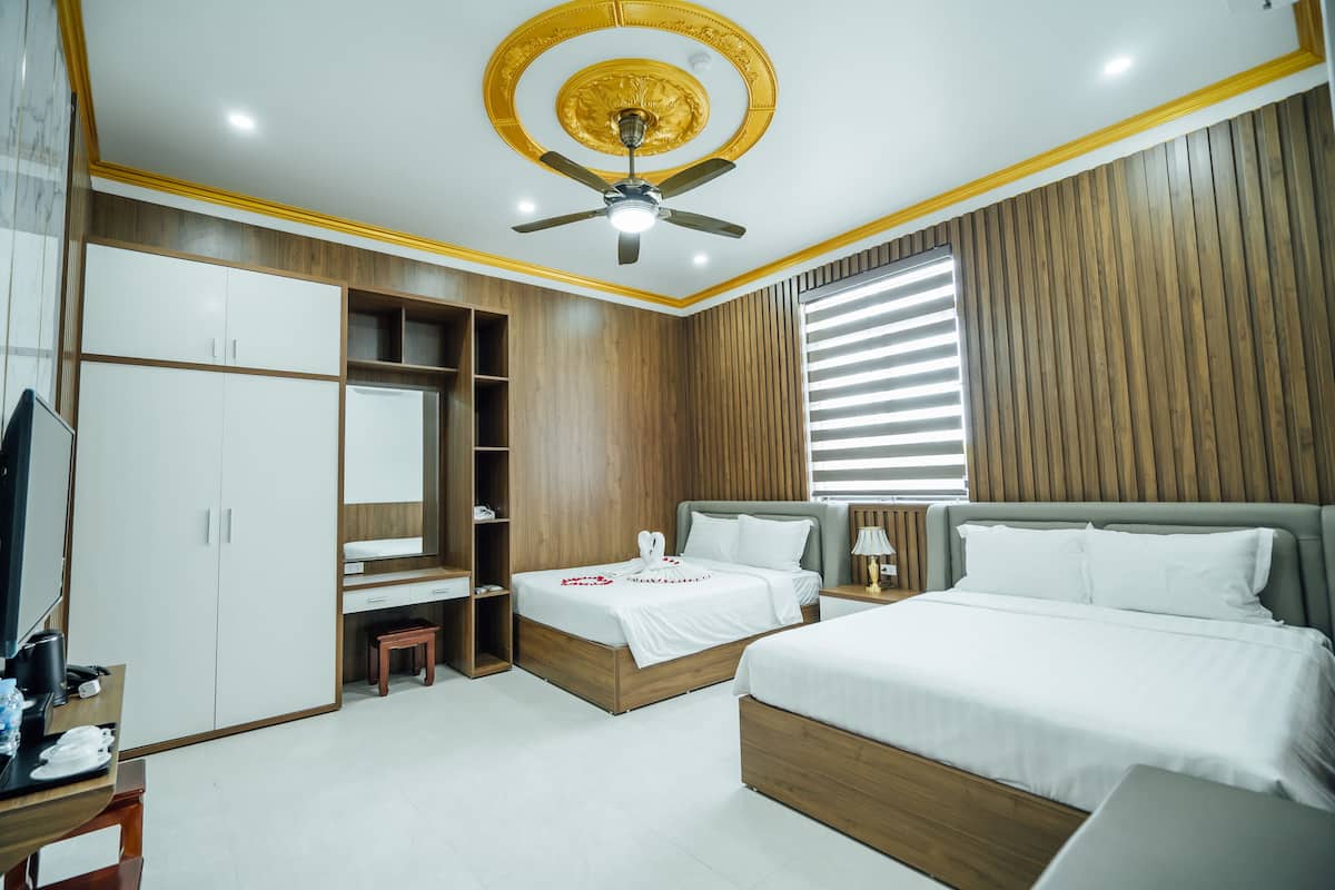 Une chambre d’hôtel moderne équipée d’un grand lit, d’un bureau, d’une armoire et d’un ventilateur de plafond.
