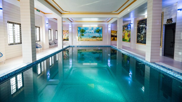 A large indoor swimming pool with clear blue water, surrounded by walls with artwork and a tiled floor. - Nam Hong Hotel (Binh Nguyen)
