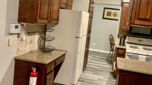 Una cocina con armarios de madera, un refrigerador blanco, una estufa y un extintor.