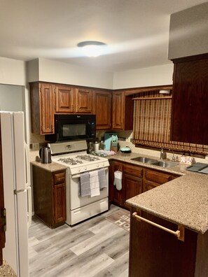A kitchen with wooden cabinets, a stove, a microwave, and a sink. - Beautiful 5 bedroom. Full access to most locations (Brooklyn Park)
