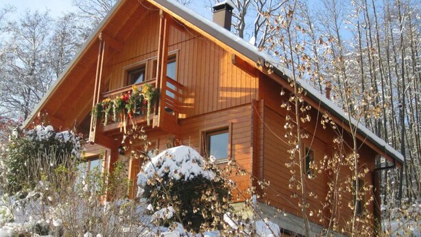 Eine Holzdiele mit Balkon, umgeben von schneebedeckten Bäumen.