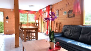 Ein Holzinterieur mit Esstisch, Stühlen, einer Couch und einer Topfpflanze.