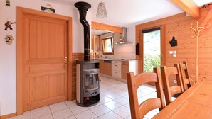 Eine moderne Küche mit Holzofen, Holzschränken und einem Essbereich mit Tisch und Stühlen.