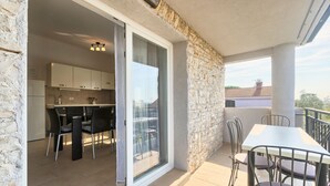 A balcony with a dining table and chairs, a kitchen area with cabinets and a refrigerator, and a stone wall. - Villa Andi Sea view, Terrace, Wi-fi, Dishwasher, Washing machine, Parking (Peroj, Vodnjan)