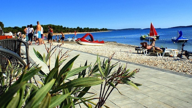 A beachside area with a paved walkway, lounge chairs, and umbrellas. - Villa Andi Sea view, Terrace, Wi-fi, Dishwasher, Washing machine, Parking (Peroj, Vodnjan)