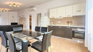 A modern kitchen with a glass dining table, dark cabinets, and a built-in oven. - Villa Andi Sea view, Terrace, Wi-fi, Dishwasher, Washing machine, Parking (Peroj, Vodnjan)