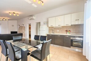 Enjoy meals at the glass-top dining table surrounded by four chairs in this kitchen with a sink and stainless steel oven.