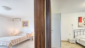 Een slaapkamer met een bed, nachtkastje en een deur.