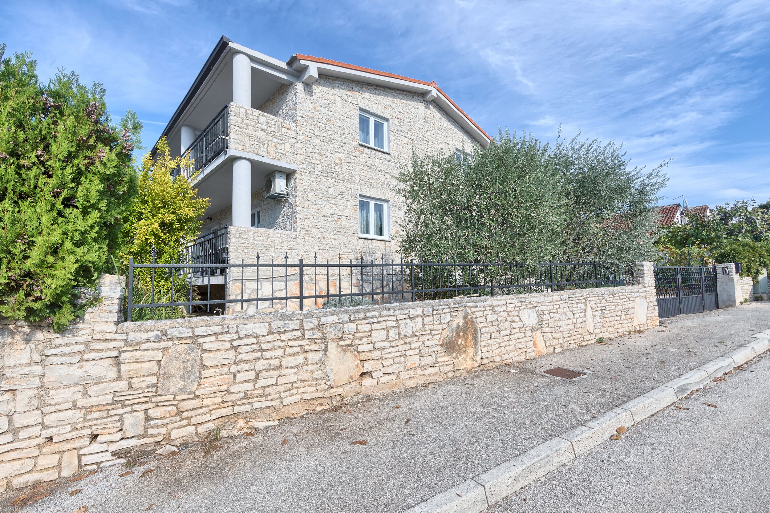 A stone building with balconies and a gated entrance.