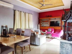 Relax in this stylish living room with a flat-screen TV, dining area, and comfortable seating.