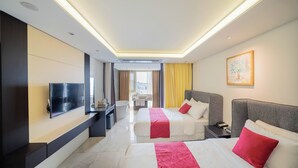 Une chambre d’hôtel moderne équipée de deux lits, d’un téléviseur à écran plat, d’un bureau et offrant une vue sur la ville.