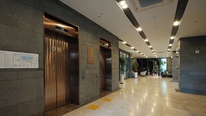 Un hall d’hôtel moderne doté de deux ascenseurs, d’un espace d’accueil et d’un sapin de Noël.