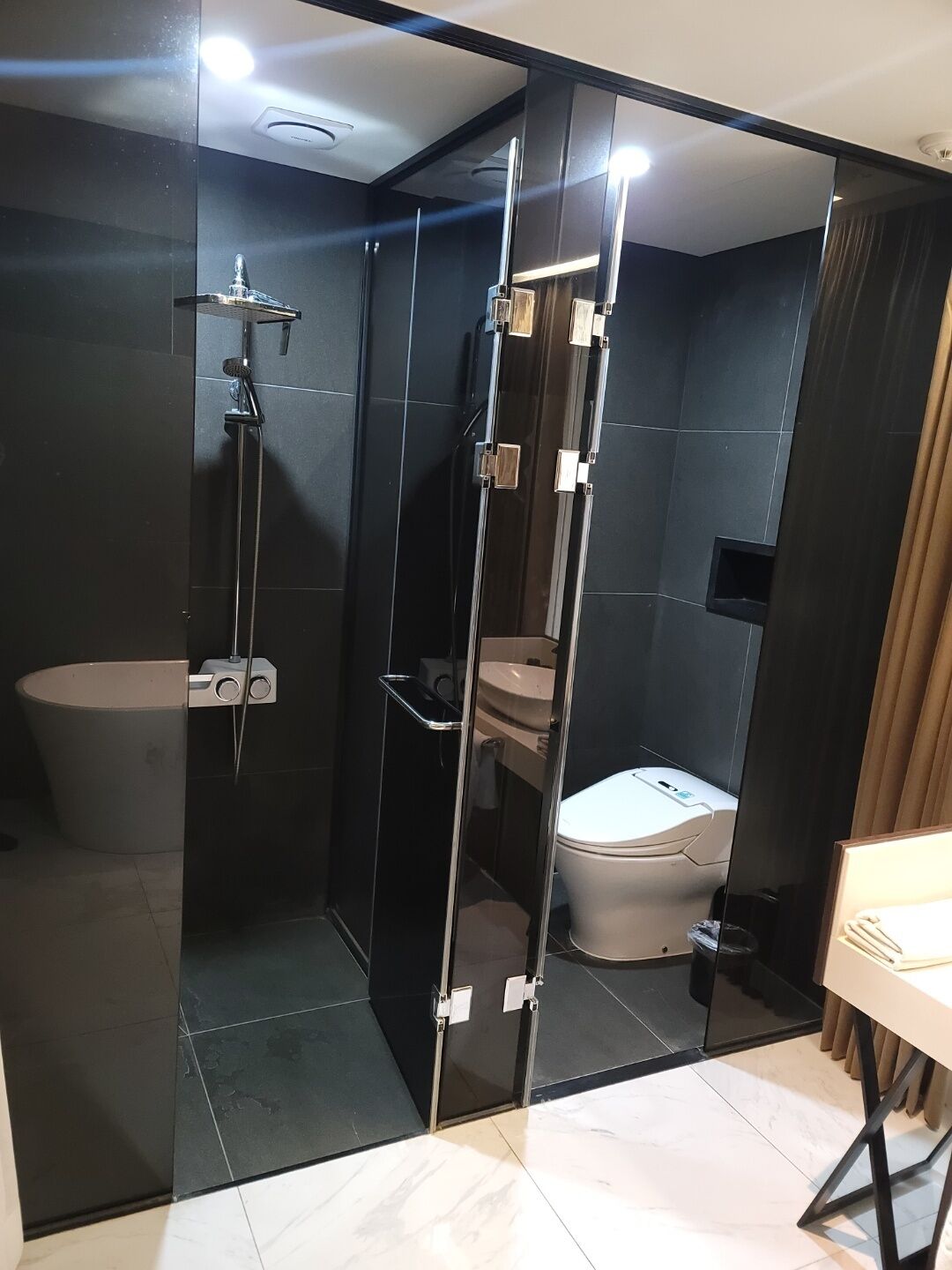 Un bany modern amb plat de dutxa tancat amb vidre, un vàter i un lavabo.