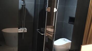 Un bany modern amb plat de dutxa tancat amb vidre, un vàter i un lavabo.