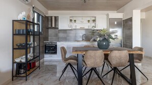 A modern kitchen with white cabinets, a built-in oven, and a dining area with a wooden table and four chairs.