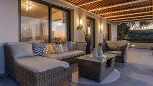 A modern outdoor living area with wicker furniture, a glass coffee table, and a view of the outdoors.
