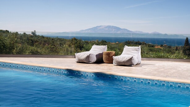 A poolside area with lounge chairs and a view of a mountain range.
