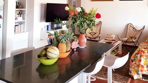 A compact living space with a kitchen area, a dining table, and a TV mounted on the wall.