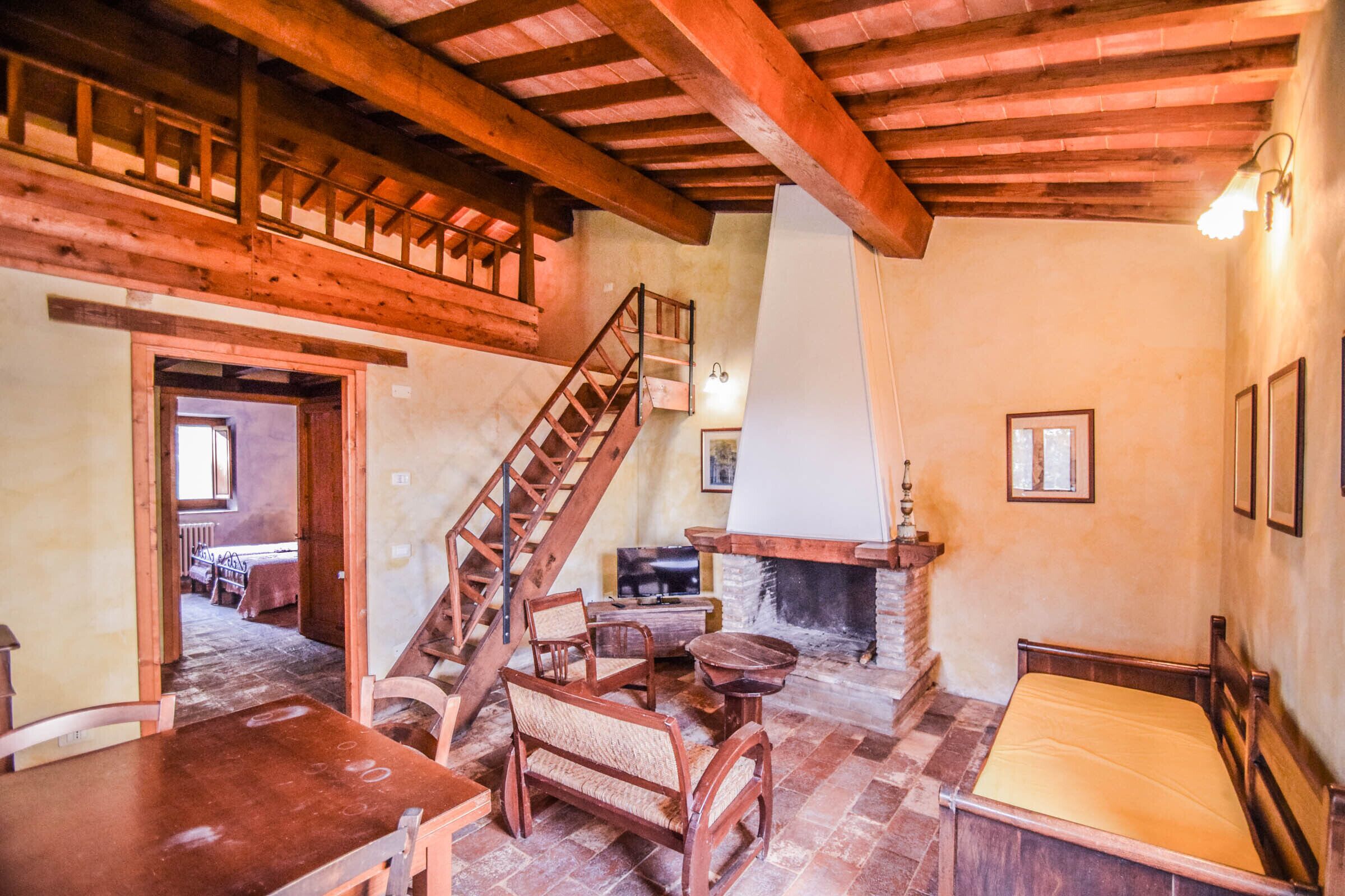 A rustic room with a wooden staircase, a fireplace, and a bed.