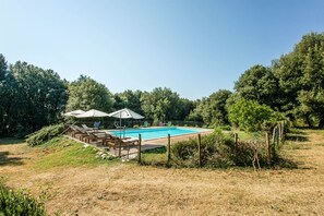 A rectangular swimming pool with a wooden deck and a fence.