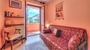 A cozy living room with a patterned sofa, a wooden chair, a small table, and a bookshelf. - Casa Elisabetta 100m From Stresa Downto (Stresa)