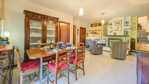 A dining area with wooden furniture, a table set with plates, and chairs with pink cushions. - Casa Elisabetta 100m From Stresa Downto (Stresa)