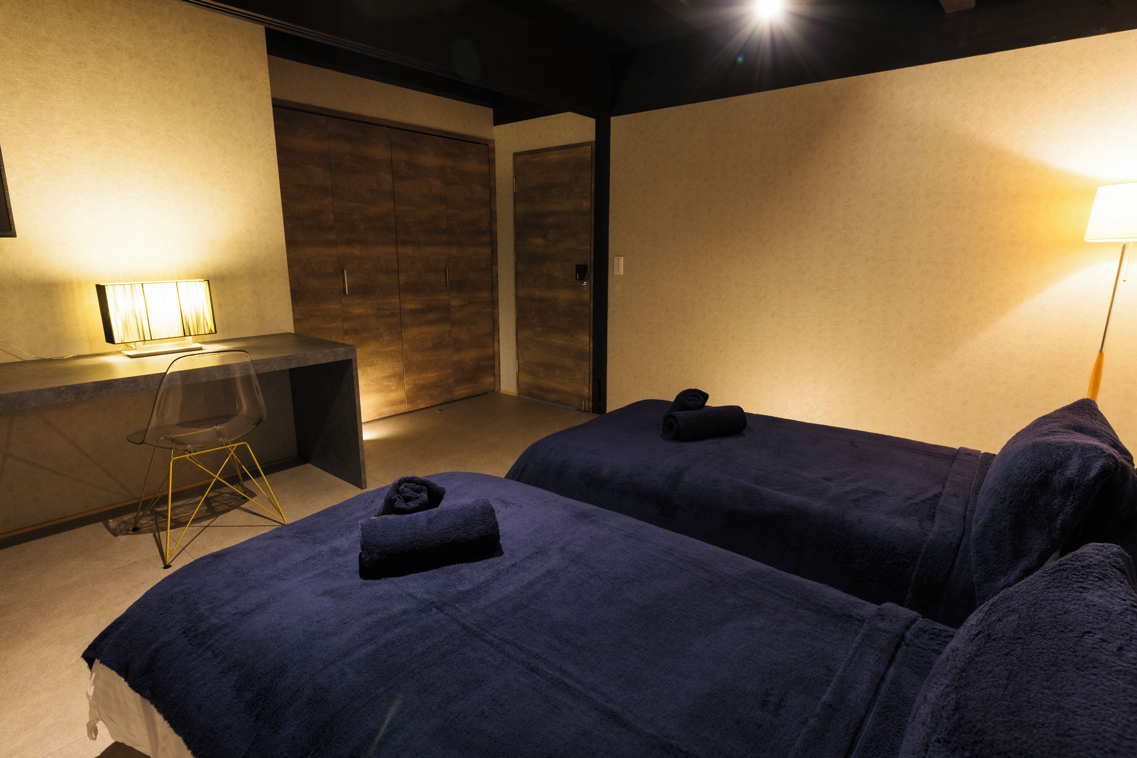 Habitación de hotel con dos camas, un escritorio y una silla.