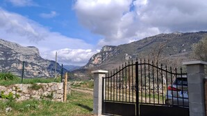 Un área vallada con montañas al fondo, un coche estacionado y cielo despejado.
