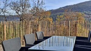 Una mesa con cuatro sillas, una cerca de madera y un paisaje montañoso al fondo.
