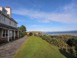 A coastal property with a stone pathway leading to a white house with multiple windows and a covered porch.