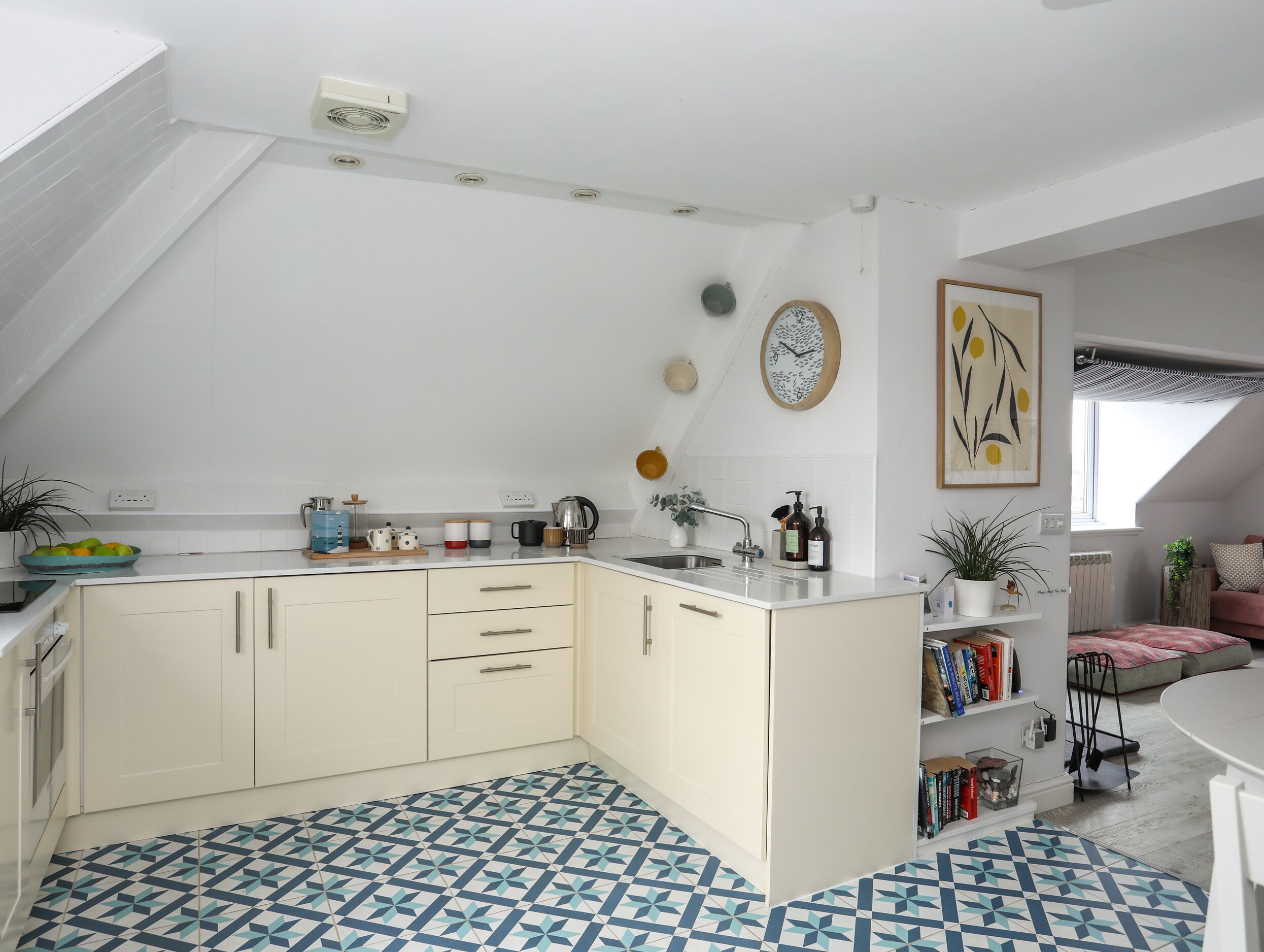 A modern kitchen with white cabinets, a built-in island, and a geometric patterned floor.