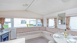 A caravan interior with a dining area, a sofa, a small table, and a mirror. - Caravan with one double and two twin. (Prestatyn, Denbighshire)