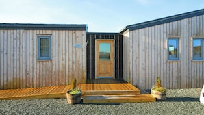 A wooden cabin with a central door, two windows on each side, and a small porch area.
