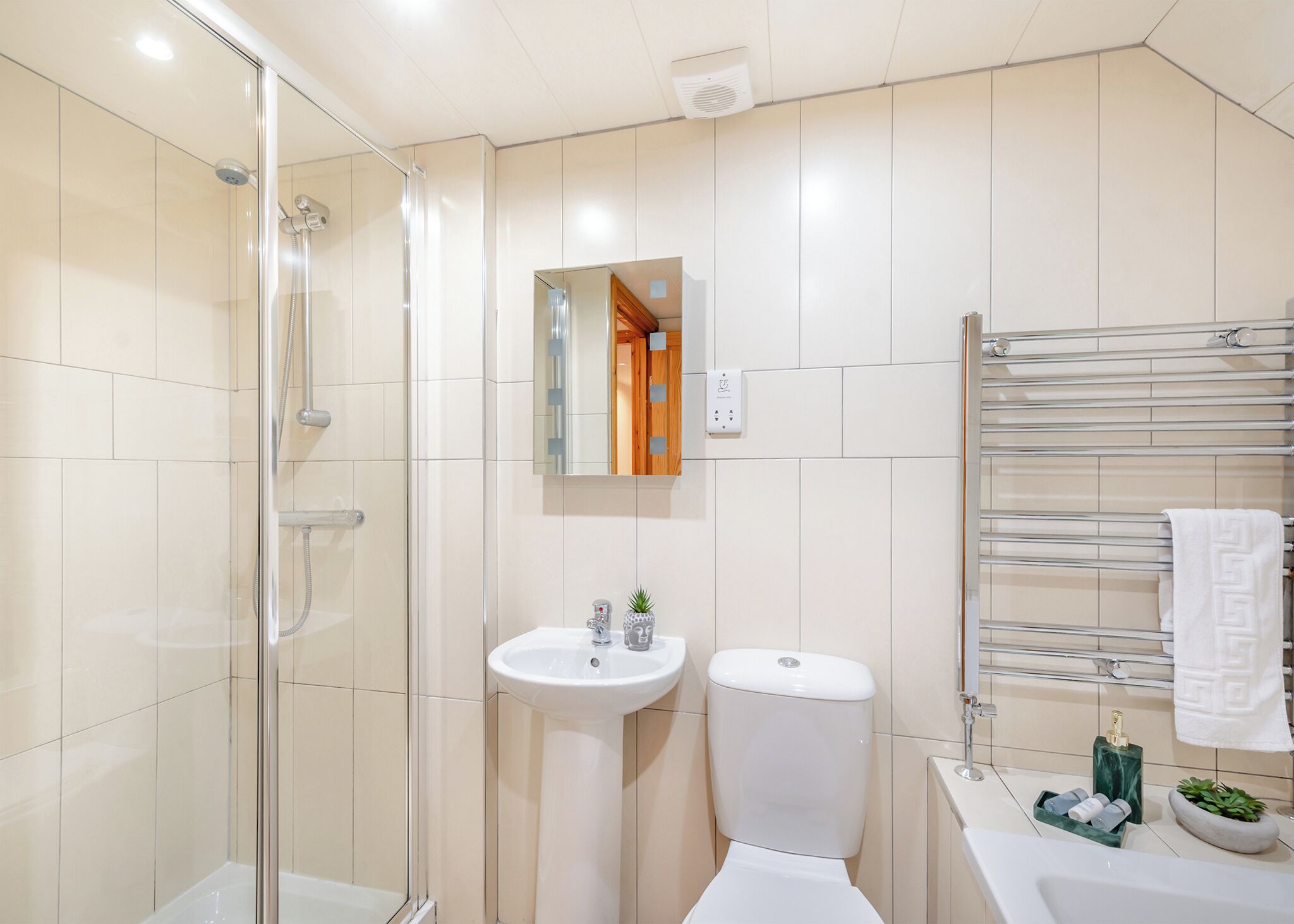 A modern bathroom with a glass shower enclosure, a pedestal sink, a toilet, and a towel rack.