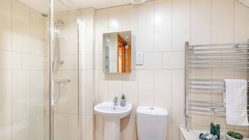 A modern bathroom with a glass shower enclosure, a pedestal sink, a toilet, and a towel rack.