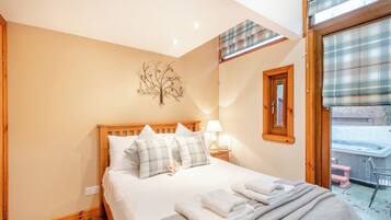 A bedroom with a bed, bedside table, lamp, and a window with blinds.