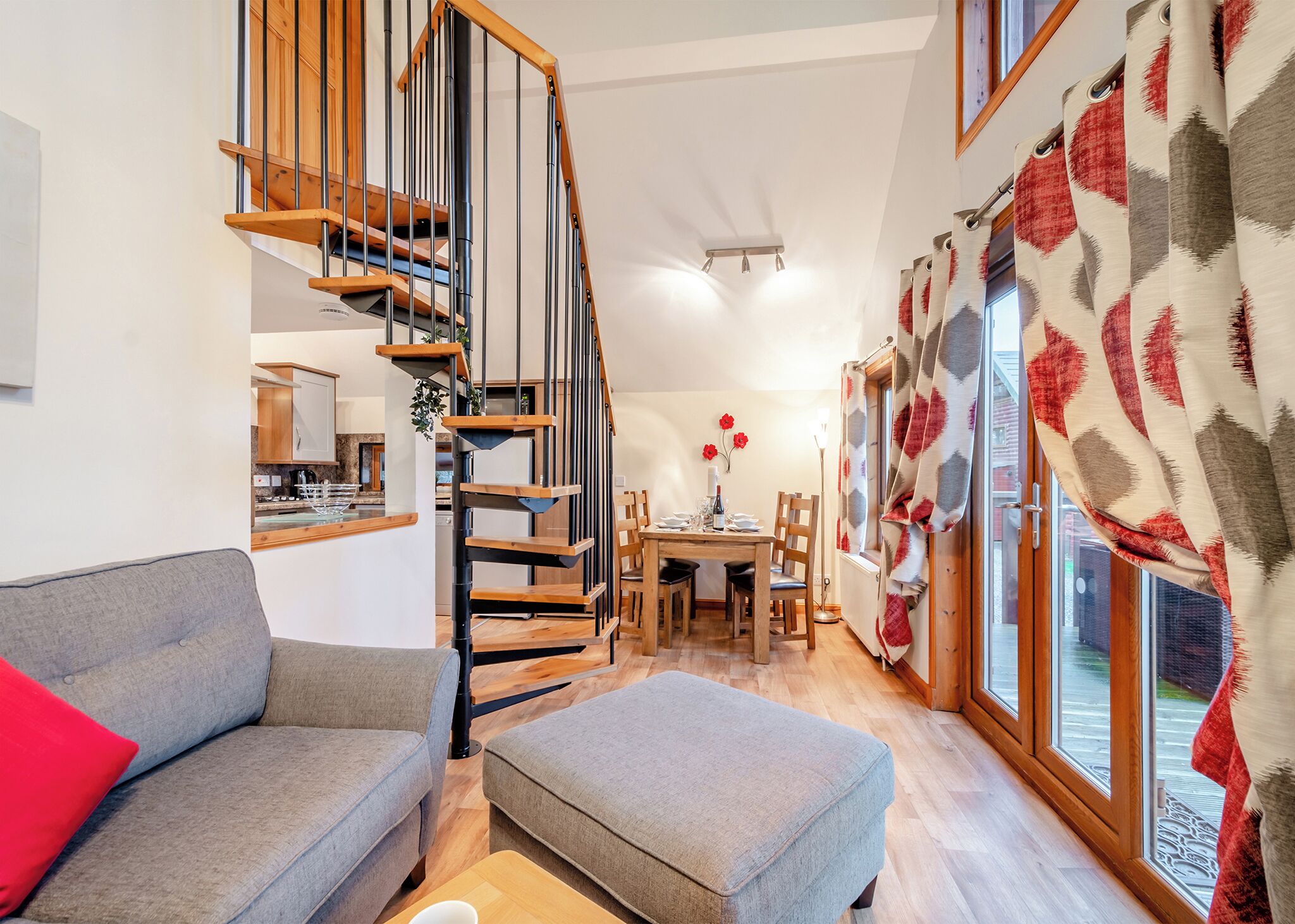 Un intérieur moderne avec un escalier, un coin repas et de grandes fenêtres.