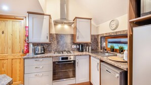 A modern kitchen with a gas stove, oven, dishwasher, and wooden cabinets.