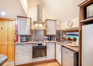 A modern kitchen with a gas stove, oven, dishwasher, and wooden cabinets.