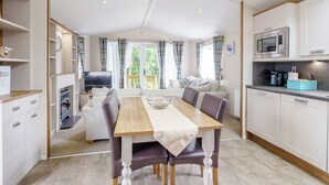 A modern, well-lit room with a dining table, chairs, a sofa, a television, and a kitchen area with a microwave. - 2 bedroom accommodation in Calthwaite, Nr Penrith (Calthwaite, Nr Penrith)